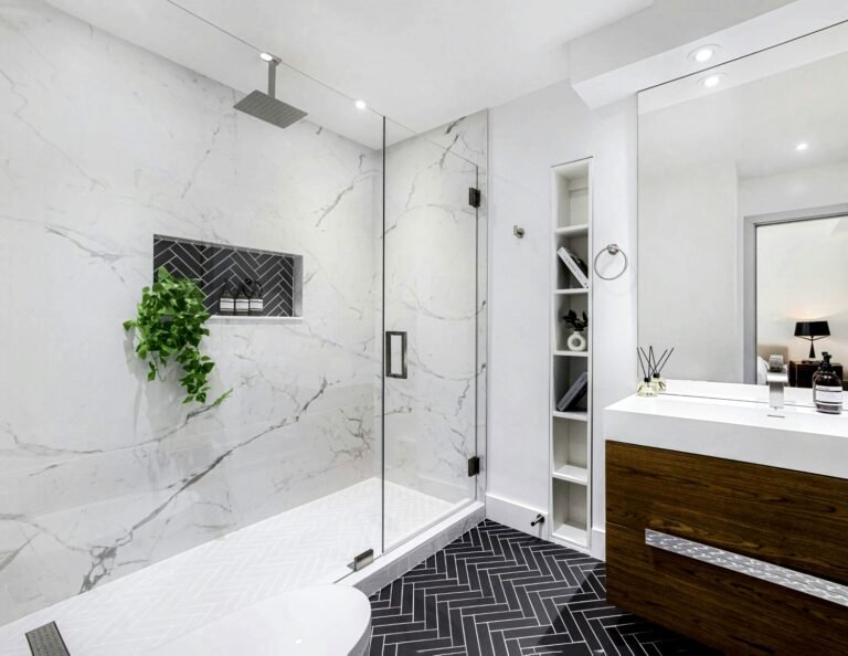 Baño reformado con ducha, azulejos blancos de gran formato, mueble de madera suspendido, espacio luminoso — ejemplo de reforma integral de calidad media en España