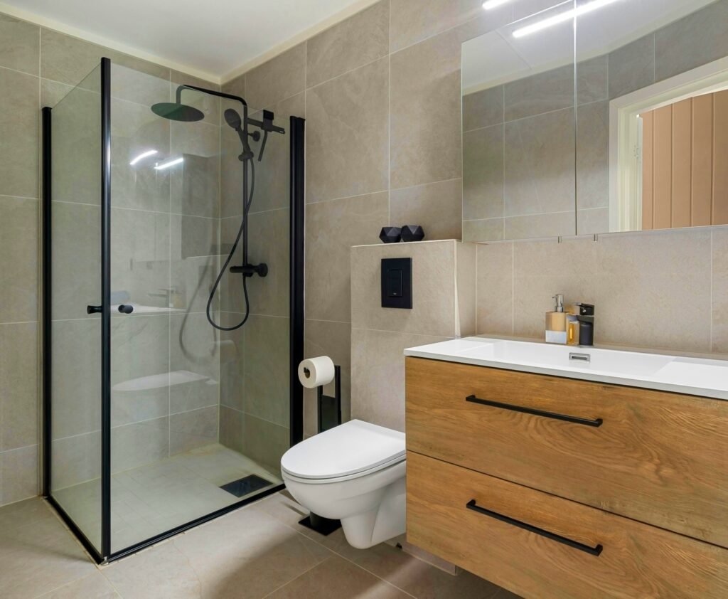Mampara de ducha con perfilería negra y cristal transparente en baño reformado