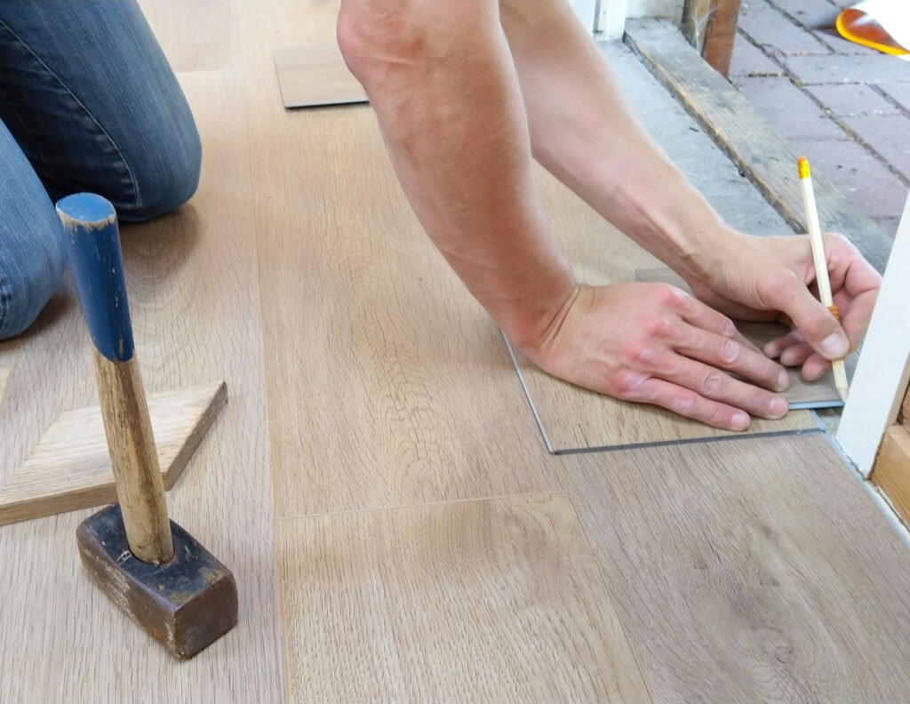 Instalador colocando suelo laminado de imitación madera en un salón durante una reforma. Sistema clic sin adhesivo.