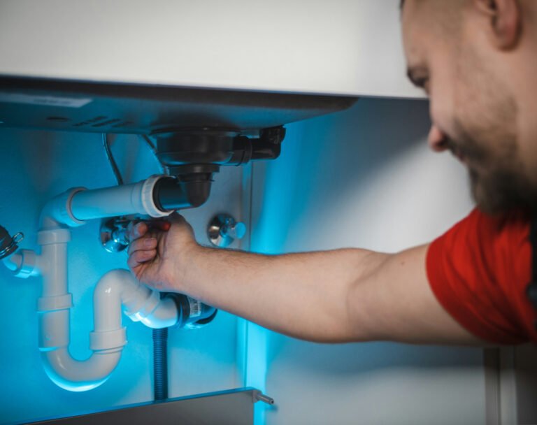 Fontanero profesional reparando tubería bajo lavabo, mano de obra fontanería en España